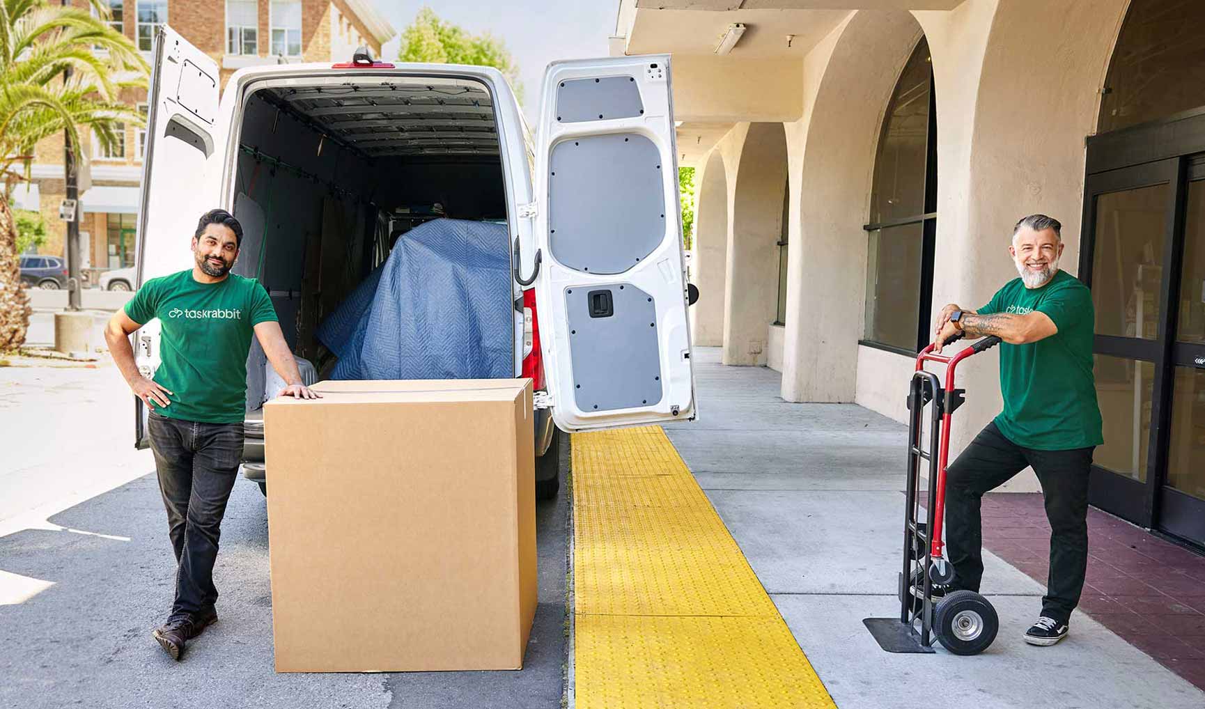 2 Dolly Helpers moving a box outside of a store